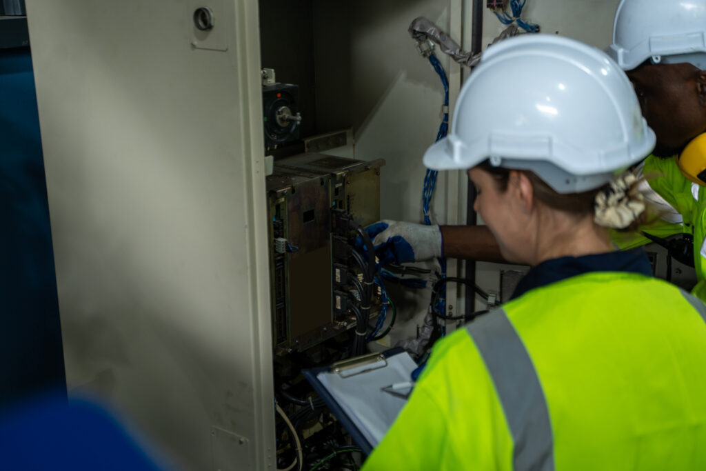 Rouhan, Ingeniero que verifica el cabezal de soldadura de la máquina robótica del brazo de soldadura con la especificación de datos en la fábrica industrial, operando el controlador de interruptor remoto para controlar la máquina robot.