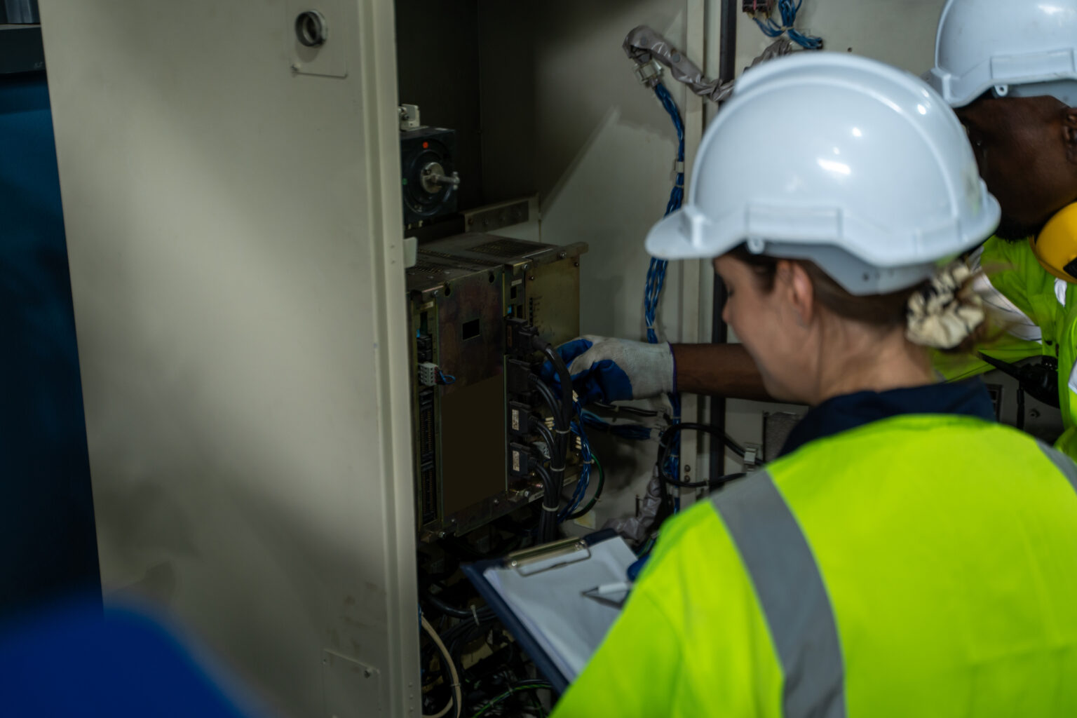 Rouhan, Ingeniero que verifica el cabezal de soldadura de la máquina robótica del brazo de soldadura con la especificación de datos en la fábrica industrial, operando el controlador de interruptor remoto para controlar la máquina robot.
